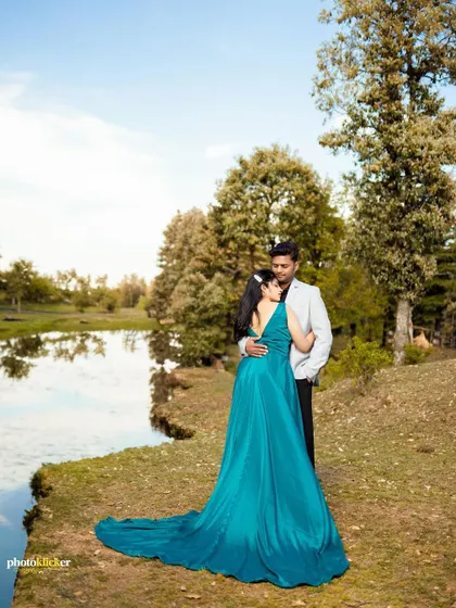A romantic portrait of a couple by a serene lake in the mountains, the woman in a beautiful teal gown, perfect for a fairytale pre-wedding shoot.
