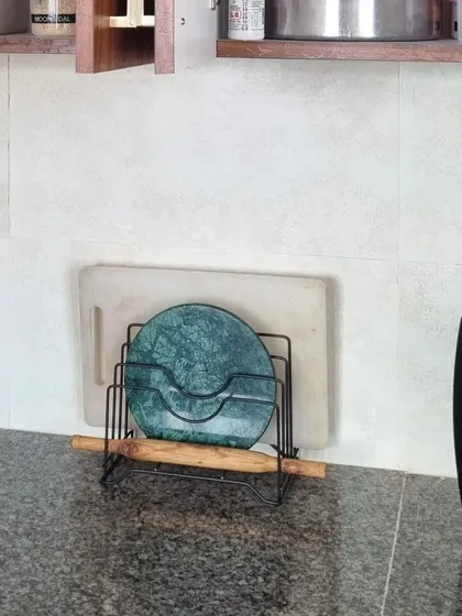 Another example of how a simple slotted organizer can keep your kitchen counter tidy. It neatly holds a marble chakla, chopping board, and rolling pin, making them easy to grab and put away.