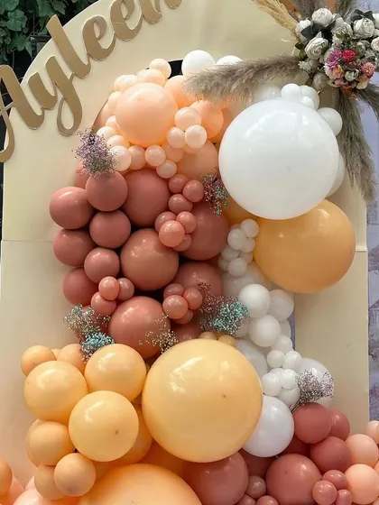 A detailed look at the custom gold 'Ayleen' name sign and the rich texture of the balloon garland.