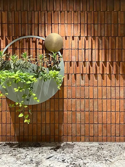 This is a piece from my Biophilic Art series, a custom wall planter against an exposed brick wall. The design symbolizes the dawn sky, with the brass element representing the sun and the green oasis depicting the earth, turning a simple wall into a story.