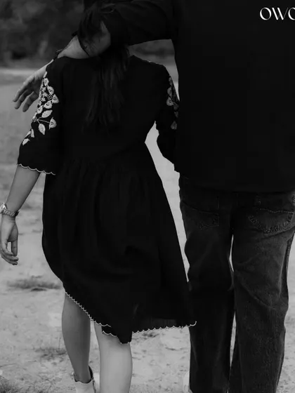 A candid black and white shot from behind, focusing on the simple gesture of a couple walking together.