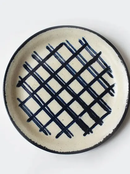 A rustic, cream-colored plate with a bold, hand-painted blue hashtag pattern. This piece is part of our eclectic collection that adds a playful touch to your tableware.