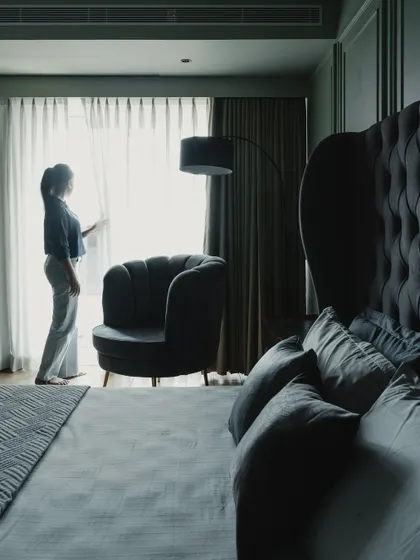 A dramatic and moody bedroom I designed, featuring a grand, deep-tufted wingback headboard. The silhouette against the window creates a sense of intimacy and luxury.