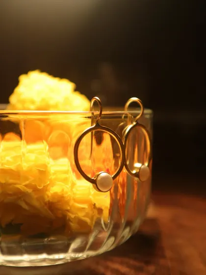 From offering to adornment, it’s a circle that never breaks. These simple and elegant gold-plated hoops with a single pearl rest on a bowl of marigolds.