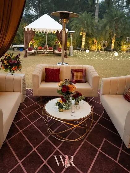 A comfortable seating arrangement within the lounge area. I used plush beige sofas with red and patterned cushions, set on a geometric red rug, to create a warm and inviting conversation nook.
