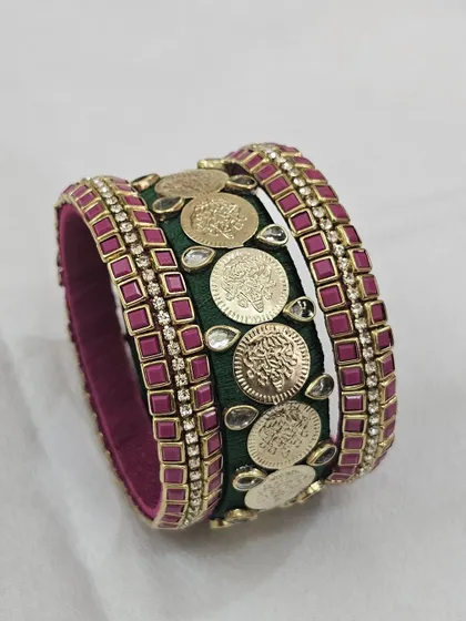A classic bridal combination of bottle green and ruby pink silk thread. This bangle set is adorned with temple coins and Kundan stones, making it a timeless choice for wedding ceremonies.