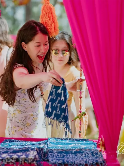Guests enjoying the interactive stalls, like choosing their own Bandhani scarves as wedding favors.