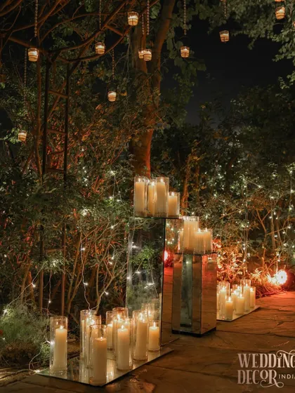 Another angle of the candlelit pathway, showing how the mirrored stands reflect the surrounding trees and fairy lights, creating a sense of infinite, sparkling space.