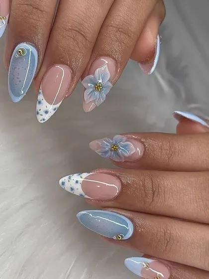 A beautiful combination of techniques. This set includes a French tip with tiny dots, a solid pastel blue, and accent nails with intricate 3D blue flowers.