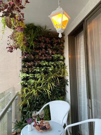 We transformed this compact apartment balcony into a cozy, private retreat. A dense vertical garden provides a lush green backdrop, perfectly complementing the small bistro table for a quiet evening with wine and conversation.