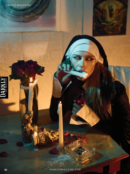 Another scene from the Darkly Magazine gothic story, with the model interacting with props at a table.