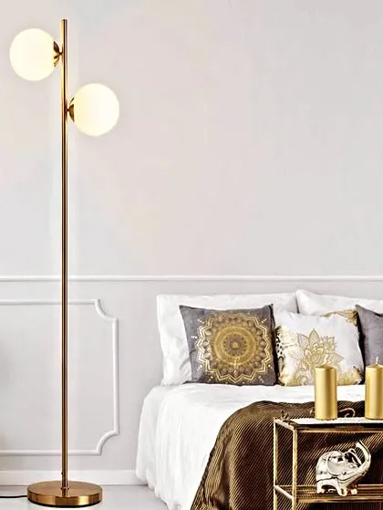 This spruce antique brass floor lamp features two glowing glass globes on a simple, elegant stand. It's a perfect choice for adding a touch of modern sophistication and warm light to a bedroom or living room corner.