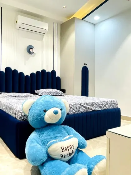 A cozy and playful bedroom we completed for a young client. The centerpiece is the custom-made bed with a deep blue, scalloped upholstered headboard that extends to the matching wardrobe doors, creating a cohesive and fun design.