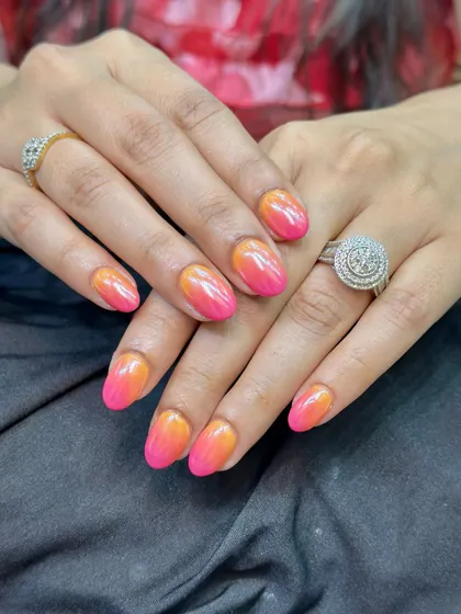 A full view of the stunning pink and orange ombre nails with a chrome finish. The colors blend seamlessly, creating a warm, tropical vibe that really pops.