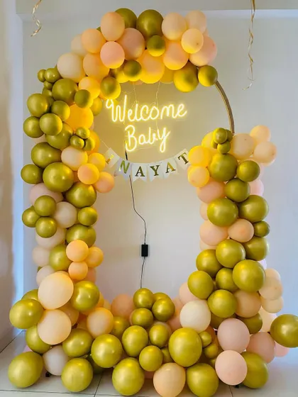 A closer look at the gold and peach "Welcome Baby" balloon ring, highlighting the beautiful color combination.