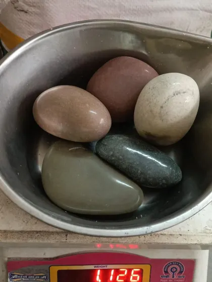 A bowl of large, smooth, polished river stones in various natural earth tones.
