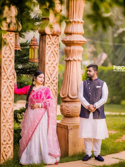 A romantic portrait of a couple in a garden. The bride's beautiful pink and white lehenga and the groom's matching outfit create a soft and elegant look.