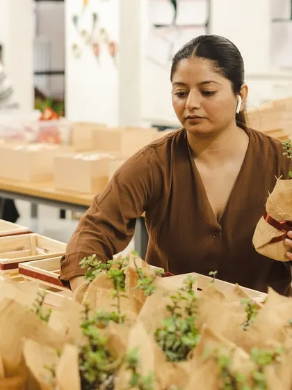 Our team member carefully placing jute-wrapped succulents into the pinewood trays for the Raphe Women's Day order. Handling delicate items is part of our expertise.