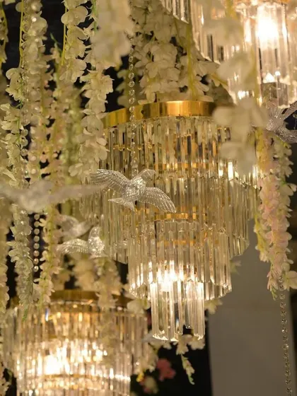A close-up of elegant crystal chandeliers adorned with small bird figures, adding a touch of whimsy to a grand setup.