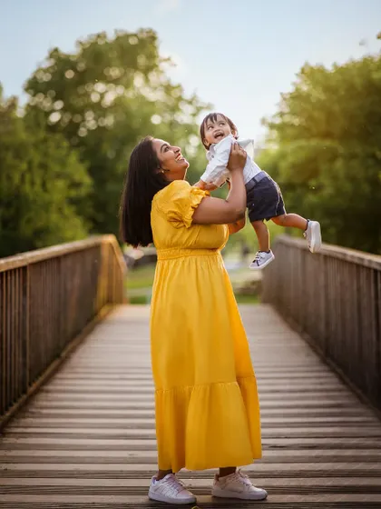 365 days of joy! A mother lifts her baby boy into the air on a wooden bridge, a perfect picture of happiness and love to celebrate his first birthday.