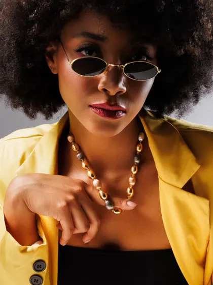 When the jewellery speaks, the light listens. The vibrant yellow blazer provides a perfect color contrast to the gold necklace, while the model's direct gaze holds your attention. This is how we create bold, fashion-forward product shots.