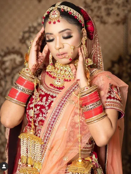 A timeless bridal pose featuring a classic red and gold Kundan jewellery set. This complete rental includes the sheesh patti, choker, and nath for a picture-perfect wedding day.