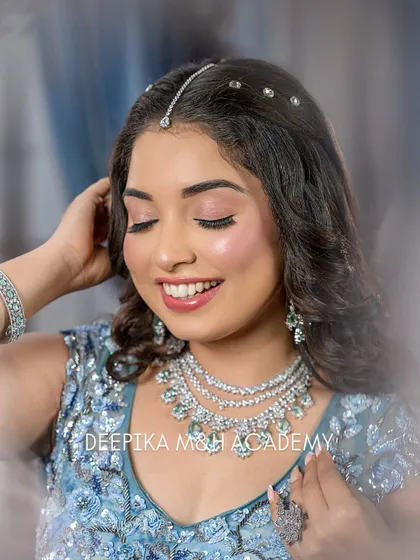 A happy and radiant party look. The model is wearing a beautiful blue embellished gown with diamond jewelry, and her makeup is fresh and glowing with a lovely smile.