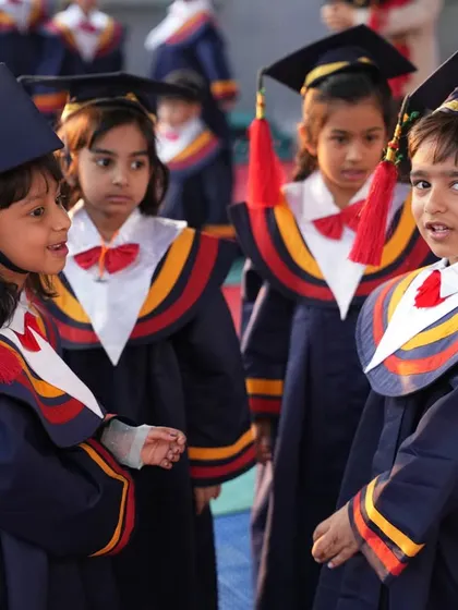 Our graduates. Children in their caps and gowns share a moment before the ceremony, celebrating their journey through Montessori.