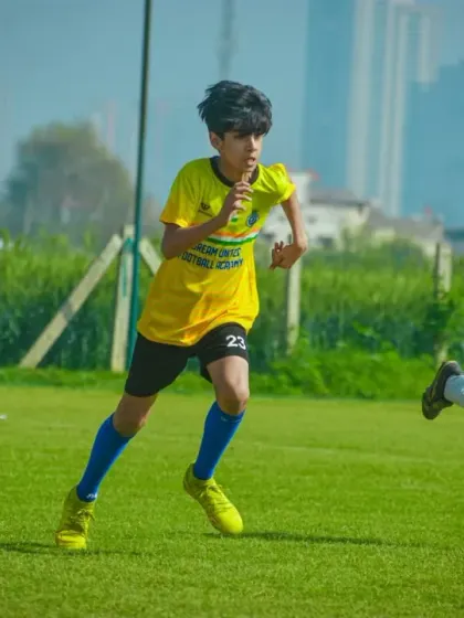 Players race towards the ball against the backdrop of Gurgaon's high-rise buildings.