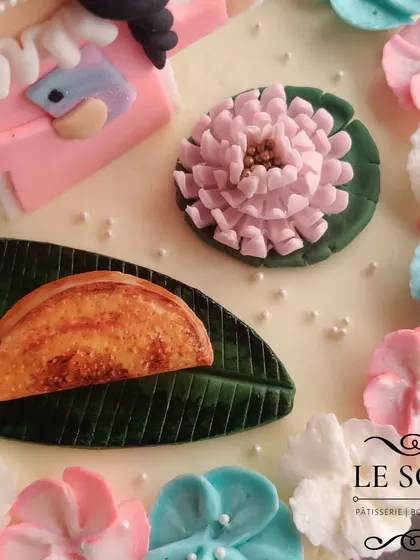 This is a close-up of a custom cake, showing the detailed fondant and buttercream work. I love adding personal touches like this miniature dosa on a banana leaf for a client's birthday.