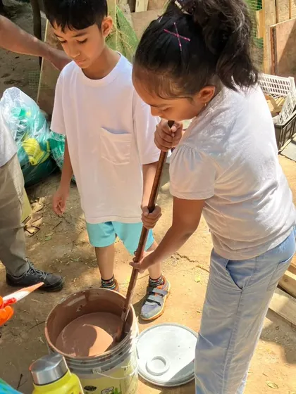 Teamwork in action. A child stirs a bucket of paint, preparing to help with the upkeep of the animal enclosures at the PfA shelter.