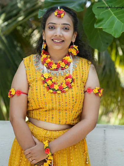 A lovely bridal portrait during her Haldi ceremony. The floral jewelry and yellow attire are beautifully complemented by the natural outdoor lighting, creating a fresh and vibrant image.