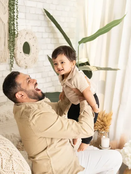 Pure joy as a father lifts his son into the air. The genuine laughter and connection in this photo make it a perfect capture of a happy family moment.