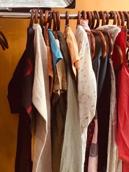 A rack of our naturally dyed clothing, showcasing the variety of colors and styles we offer. From deep indigos and earthy reds to soft whites, every piece is made from natural fabrics like cotton and khadi.