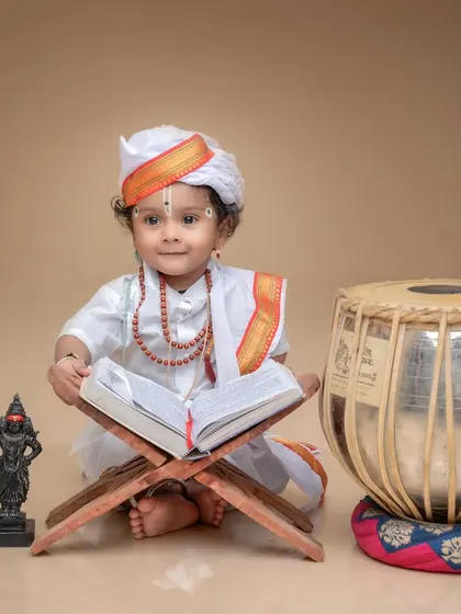A little Varkari devotee sits with a holy book and a tabla. This pose captures the musical and spiritual essence of the Varkari tradition.