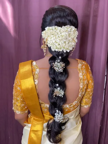 A classic South Indian bridal hairstyle. This features a bubble braid adorned with beautiful hair accessories and fresh jasmine flowers, perfect for a Muhurtham.