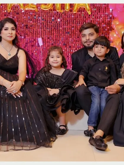 A beautiful family portrait from Taisha's birthday. Everyone is dressed in coordinated black outfits, creating a stylish and unified look against the festive pink backdrop.
