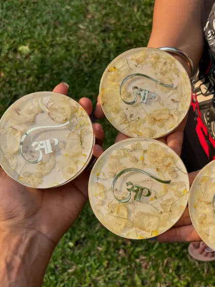 Holding a set of four custom coasters with preserved flowers and a personalized logo. They are a great example of a small, meaningful, and functional piece of art.