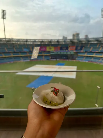 A delicate dumpling held against the backdrop of the Wankhede stadium. A moment of culinary calm before the match.