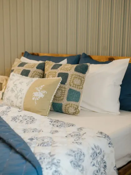 Another angle of this beautifully styled bed, showing a different arrangement of our custom cushion covers. The mix of floral prints, embroidery, and patchwork adds depth and personality to the space.