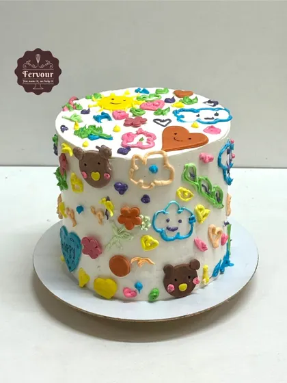A fun and colorful doodle cake. The white whipped cream serves as a canvas for cute, hand-piped doodles, creating a playful and artistic design.