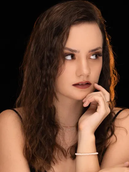 A thoughtful and classic portrait against a dark background. The lighting is soft and flattering, creating a timeless look.
