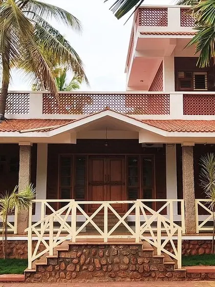 The entrance to the 'Grid in the Grove' farmhouse. The design uses terracotta jali parapet walls and unfinished granite columns, inspired by the architectural splendor of nearby Hampi.