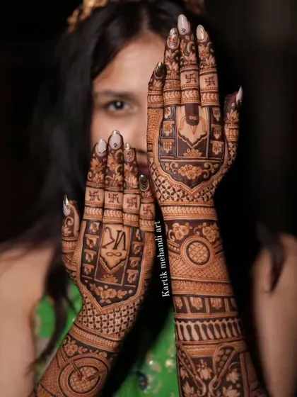 A close-up of the back-hand design with the 'VK' initials and a Ganesha portrait. This is a perfect example of our personalized and traditional mehandi.