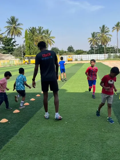 A coach guides young players through agility and coordination exercises on the training ground.