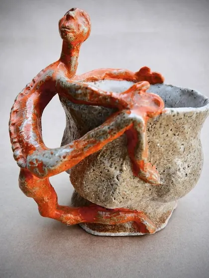 A cup from my 'Supervision' series. A hand-pinched, textured cup is embraced by a sculptural human figure that forms the handle. It explores the connection between the user and the object.