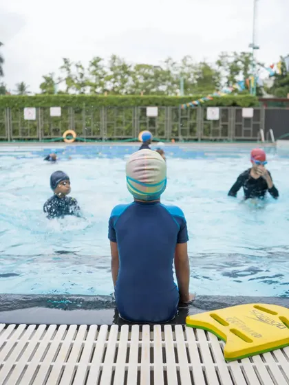 A young swimmer takes a moment to watch their peers. We foster a supportive environment where students learn from coaches and each other.