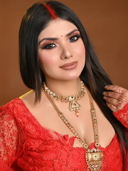 A classic Indian bridal look with a red bindi and sindoor. The makeup features a warm-toned smokey eye and a defined winged liner, created by an MBM student.
