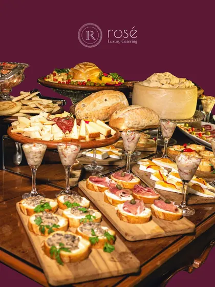 A lavish charcuterie and cheese board featuring various breads, cured meats, and cheeses. This type of grazing platter is a fantastic centerpiece for a sophisticated cocktail event.