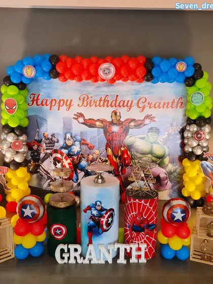 An action-packed party with a superhero theme. This setup includes a large backdrop with all the favorite Avengers, character cutouts, and balloon columns in the colors of Iron Man, Hulk, and Captain America.
